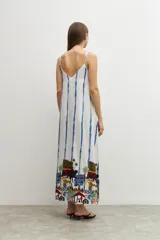 Maxi vestido blanco con rayas verticales azules y estampado de paisaje en el ruedo.