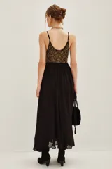 Vestido largo de fiesta con escote en V profundo y tirantes finos. Presenta un cuerpo superior bordado con lentejuelas doradas y una falda fluida de color negro con caída suave.