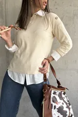 Sweater beige de hilo con cuello camisero blanco y botones decorativos en los hombros.