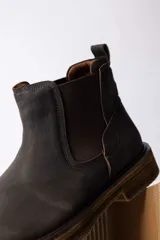 Bota tipo Chelsea de cuero color marrón oscuro, con paneles laterales elásticos y suela de goma con efecto madera.