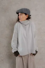 Sweater de punto color gris claro, con cuello alto, mangas largas y corte holgado.