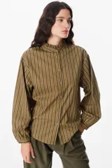 Camisa de manga larga con estampado de rayas verticales en color bordó y blanco. Presenta un cuello alto con volados y cierre frontal con botones a tono.