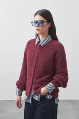 Cardigan de textura suave y efecto fluffy, con cuello redondo y cierre frontal de botones. Presenta mangas largas con puños ajustados y una silueta relajada.