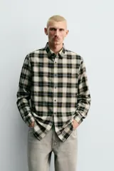 Camisa de corte relaxed fit confeccionada en una mezcla de lana y algodón. Presenta un diseño de cuadros, cuello solapa, manga larga con puños abotonados y cierre frontal con botones.