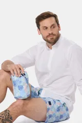 Short de baño celeste con estampado tropical de hojas en tonos azules y rosados, con cintura elastizada y cordón ajustable.