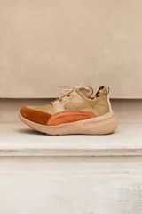 Championes deportivos de cuero en tonos marrón, tostado y marrón oscuro, con detalles de estampado animal print de leopardo en el lateral, suela gruesa blanca y cordones elásticos.