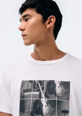 Camiseta blanca de algodón con cuello redondo y mangas cortas. Estampa rectangular con borde negro que contiene la frase "NATURAL ATMOSPHERE" en letras mayúsculas y una imagen de montañas y mar.