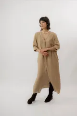 Vestido largo de lino color tostado, de manga larga, con escote redondo y diseño amplio y fresco. Cuenta con un delicado bordado en la espalda con motivos marinos y la frase "no se lo digas".