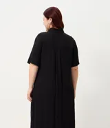 Vestido chemise midi color negro confeccionado en viscosa, de corte recto y holgado. Cuenta con cuello camisero, mangas cortas y cierre frontal con botones al tono.