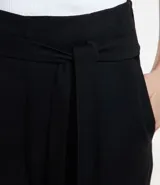 Pantalón de vestir gris, de corte zanahoria, con lazo en la cintura y pliegues frontales.