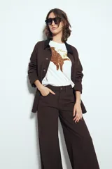 Pantalón de pierna amplia color beige, con silueta relajada y calce cómodo, confeccionado en denim con leve elasticidad. Presenta costuras a contraste.