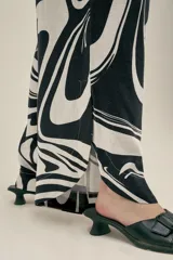 Pantalón ancho con estampado abstracto en blanco y negro, con pinzas en el frente, bolsillos laterales y elástico en la cintura.