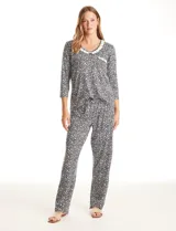 Conjunto de pijama compuesto por una remera de manga larga y un pantalón largo, ambos con estampado floral en blanco y negro. La remera presenta escote redondo con detalle de encaje tipo crochet, un pequeño bolsillo frontal con el mismo detalle y un lazo decorativo. El pantalón cuenta con cintura elástica y lazo de ajuste.