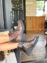 Botas cortas de cuero color chocolate, con elástico lateral, cierre interno con cremallera roja, pespuntes rojos y suela track.