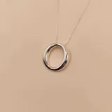 Conjunto de collar y aros plateados de plata 925. El collar tiene una cadena fina y un dije circular. Los aros son argollas gruesas.