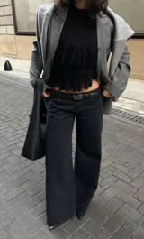 Pantalón de jean estilo wide leg, de tiro bajo y corte recto, en color negro lavado. Presenta costuras reforzadas y diseño de cinco bolsillos.