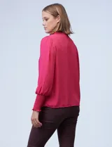 Blusa blanca de gasa con cuello a la base, escote en V y botones. Presenta punto smock en hombros y puños.