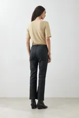 Pantalón de jean negro, tiro alto, corte cropped y botamanga acampanada.