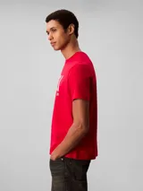 Remera Calvin Klein de color rojo, con cuello redondo, mangas cortas y corte regular. Presenta el logotipo y monograma de la marca impresos en gran tamaño en el centro del pecho.