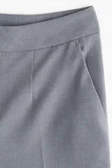 Pantalón sastrero gris de tiro alto, con pliegues marcados al frente y piernas anchas y rectas.