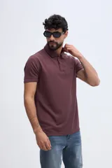 Remera polo bordó con textura sutil, cuello y puños acanalados con línea oscura de contraste, cierre frontal parcial de dos botones y logo bordado en el pecho.