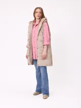 Chaleco largo acolchado color beige, con capucha forrada en sherpa, cierre frontal con cremallera y botones a presión, y bolsillos laterales.