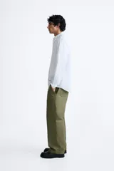 Camisa celeste a rayas verticales, de corte relaxed fit, confeccionada en lino y algodón. Tiene cuello abotonado, manga larga con puños abotonados, bolsillo de parche en el pecho y cierre frontal con botones.