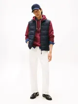 Chaleco acolchado de nailon reciclado, color azul marino, con cuello alto y cierre frontal de cremallera. Presenta el logo de Tommy Hilfiger bordado en el pecho.