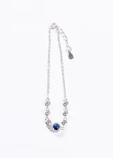 Pulsera de plata 925 con cadena de eslabones finos y engarces de circonitas blancas redondas. El dije central es una circonita azul redonda rodeada por un halo de circonitas blancas más pequeñas, con un colgante de lágrima en el cierre.