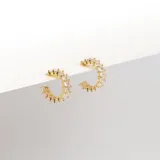 Par de aros tipo argolla abiertos, color dorado, cubiertos con cristales claros.
