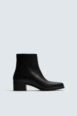 Bota de piel negra con cierre de cremallera lateral, horma cuadrada y tacón de 5 cm.