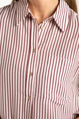 Camisa de corte oversize con estampado de rayas verticales, cuello clásico, cierre frontal con botones y bolsillo en el pecho. Presenta mangas largas con puños abotonados y un diseño fluido.