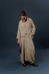 Pollera larga de lino color gris topo, de diseño amplio con volumen, movimiento y bolsillos delanteros. Cuenta con elástico en la cintura y detalles de pinzas y sobretelas en los laterales.
