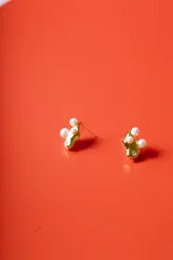 Par de aros dorados con textura irregular, adornados con tres perlas blancas y un pequeño cristal brillante.