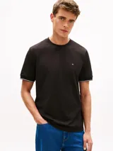 Remera de corte slim color negro con mangas cortas, cuello redondo y detalle de doble raya blanca en los puños. Presenta el icónico logo bordado de la marca en el pecho.