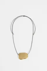 Collar con cordón negro ajustable y dije central de forma orgánica en color dorado con acabado brillante.