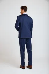 Ambo de corte slim compuesto por saco de dos botones y pantalón de vestir a juego, en color azul marino. El saco presenta solapas clásicas, bolsillos laterales con solapa y bolsillo en el pecho con pañuelo decorativo.