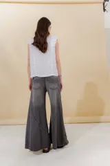 Pantalón de jean color beige, de tiro medio, corte amplio y ruedo acampanado.