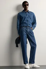 Jeans regular fit de tiro medio, confeccionados en denim de algodón azul oscuro con efecto lavado. Presenta diseño clásico de cinco bolsillos, pierna recta y cierre frontal con cremallera y botón.