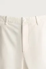 Pantalón cargo relaxed fit de color blanco, confeccionado en tejido de algodón. Presenta bolsillos de plastrón con solapa en las perneras y cierre frontal con cremallera y botón.