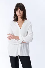 Blusa blanca de manga larga con escote en V y cierre frontal con botones.
