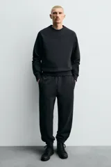 Zapatilla tipo botín de estilo minimalista fabricada en piel lisa de color negro. Presenta un diseño de caña media con cierre de cordones al tono y suela plana de goma a juego.