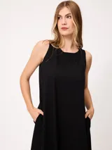 Vestido midi sin mangas de corte recto y holgado, color beige, con cuello redondo y bolsillos laterales.