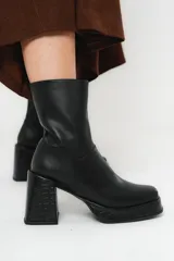 Bota de caña media color negro, de cuero, con horma cuadrada, taco geométrico con textura símil cocodrilo y plataforma.