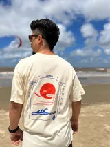 Remera color crema de algodón con estampa en la espalda de un paisaje playero con el texto "Chema Sure Chate et la mer".