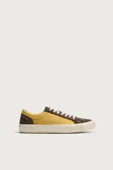 Zapatilla de estilo retro fabricada en una combinación de piel con acabado serraje y algodón, en tonos marrón y amarillo, con suela contrastada.