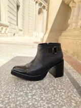 Botinetas de cuero en combinación tricolor de marrón, tostado y beige, con plataforma y taco ancho de madera. Cuenta con detalle de tira con hebilla en el lateral y cierre interno.