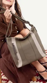 Cartera bandolera color marrón con detalles en gamuza. Tiene correa regulable, cierre metálico frontal y trasero, y división interna.