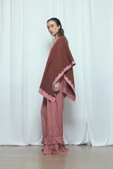 Poncho marrón con detalles de bordes ondulados en color rosado, confeccionado en mezcla de acrílico, poliéster y elastano, de diseño abierto y mangas amplias.