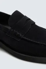 Mocasín de vestir para hombre, confeccionado en piel con acabado serraje (gamuza), color negro. Presenta un detalle de antifaz en el empeine y suela negra a contraste con un ligero tacón.